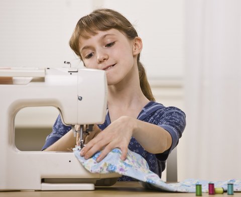 Young girl happily sewing on her refurbished sewing machines Young girl happily sewing on her refurbished sewing machines